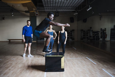 Young male sportsperson jumping on box in health studio