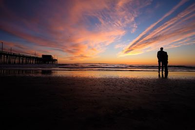 Silhouette man standing on beach against sky during sunset