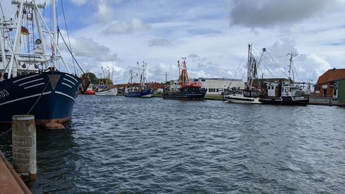 Boats moored at harbor against sky