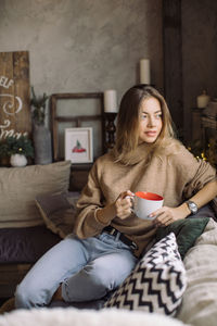 Young woman sitting on sofa at home