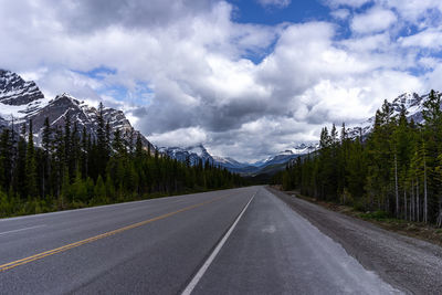 Road amidst trees and mountains against sky