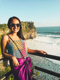 Portrait of smiling young woman on beach against clear sky