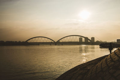 Bridge over river against sky during sunset