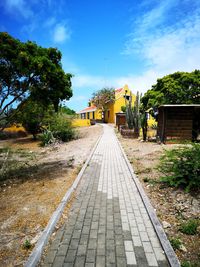 Footpath amidst buildings against blue sky