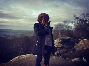 Portrait of woman with yorkshire terrier standing at brimham rocks against sky