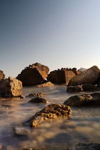 Rocks in sea against clear sky