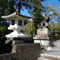 Statue by trees and building against sky