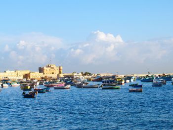 Sailboats in sea against buildings in city