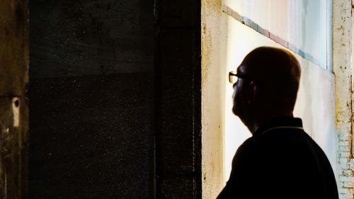 Rear view of man looking through window