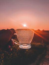 Close-up of hand holding sun against sky during sunset