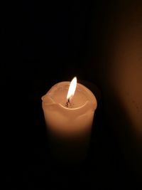 Close-up of lit candle in darkroom