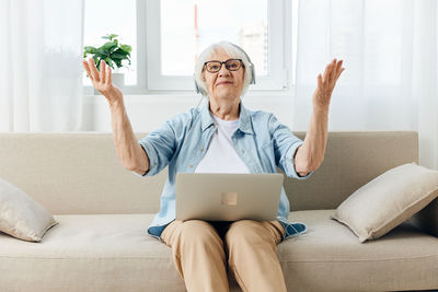 Young woman using laptop while sitting on sofa at home