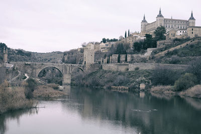 Arch bridge over river against buildings