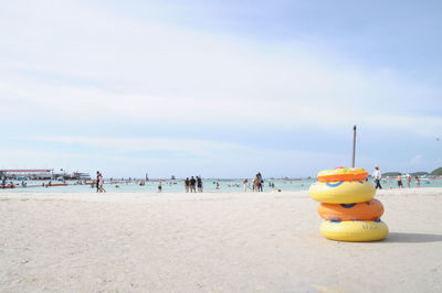 Stack of inflatable rings on shore against cloudy sky