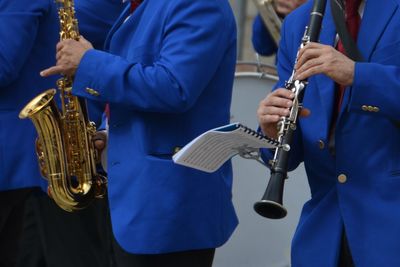 Midsection of musicians playing wind instruments