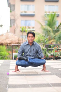 Portrait of young man sitting on footpath