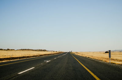 Empty road along landscape against clear sky