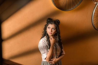 Portrait of beautiful young woman standing against wall