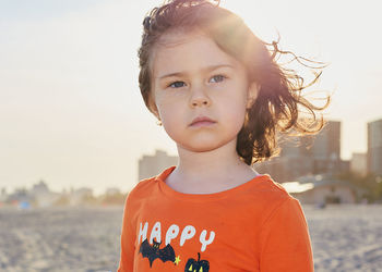 Young girl is playing on the beach on a warm day in a halloween shirt