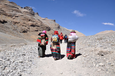 Full length of people relaxing on mountain against clear sky