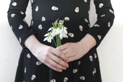 Midsection of woman holding white flowers