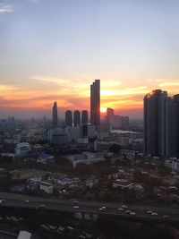 Modern buildings in city against sky during sunset