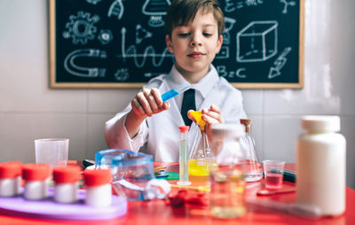 Boy wearing lap coat while sitting in classroom