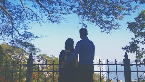Silhouette people standing by tree against sky