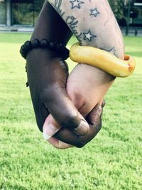 Close-up of man holding hand on field