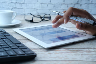 Man's hand working on digital tablet at office desk, using self created chart.