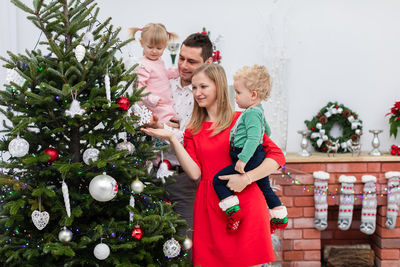 Portrait of siblings playing with christmas tree at home