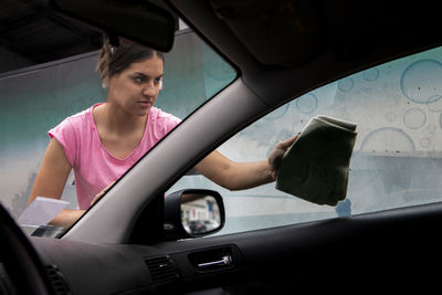 Satisfied teen girl polishing his car with microfiber cloth. close-up