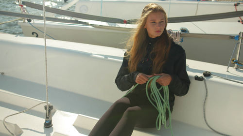 Girl holding rope while sitting on nautical vessel