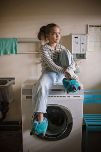 Teenage girl using common laundry to save resources and money. sustainability and environment care