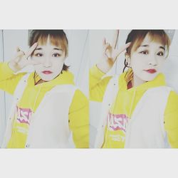 Close-up portrait of cute girl standing against yellow wall