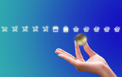 Cropped hand of woman holding trophy against blue background