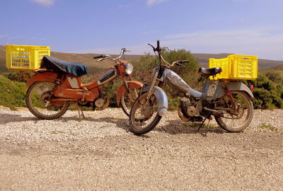 Bicycles parked on road amidst field against sky