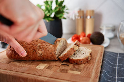 Woman cutting loaf of bread with large knife