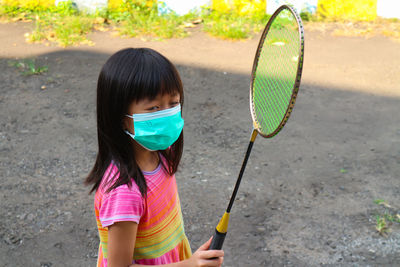 Girl wearing medical mask an playing badminton in the front house