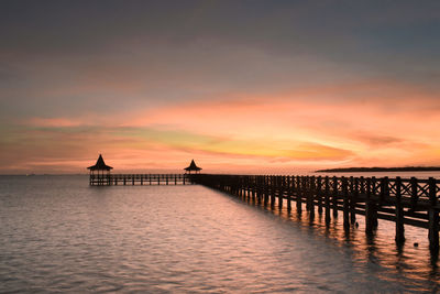 Silhouette pier over sea against sky during sunset