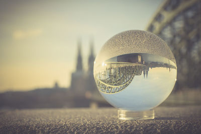 Close-up of crystal ball on glass against sky