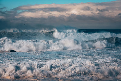 Waves splashing on sea against sky