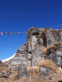 Low angle view of flags against clear blue sky