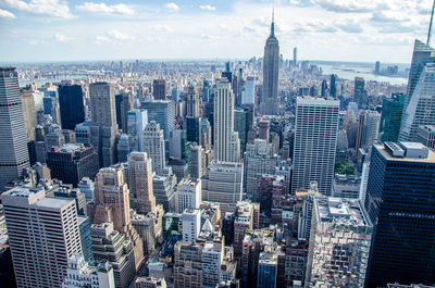 Aerial view of buildings in city against cloudy sky