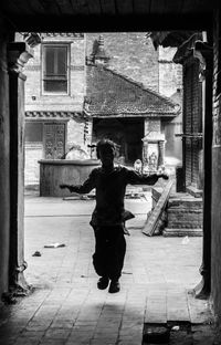 Full length rear view of man standing on cobblestone