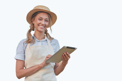 Portrait of smiling young woman using smart phone against white background