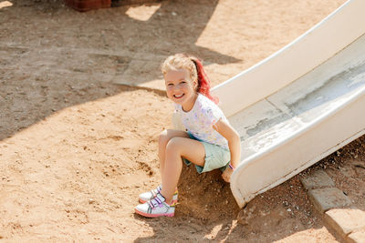 Cute little girl rides down a slide on the playground