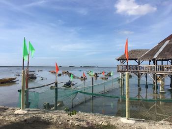 Orange and green flags at beach against sky