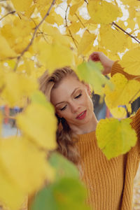 Portrait of smiling young woman against yellow flowering plants