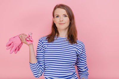 Portrait of smiling woman standing against pink background